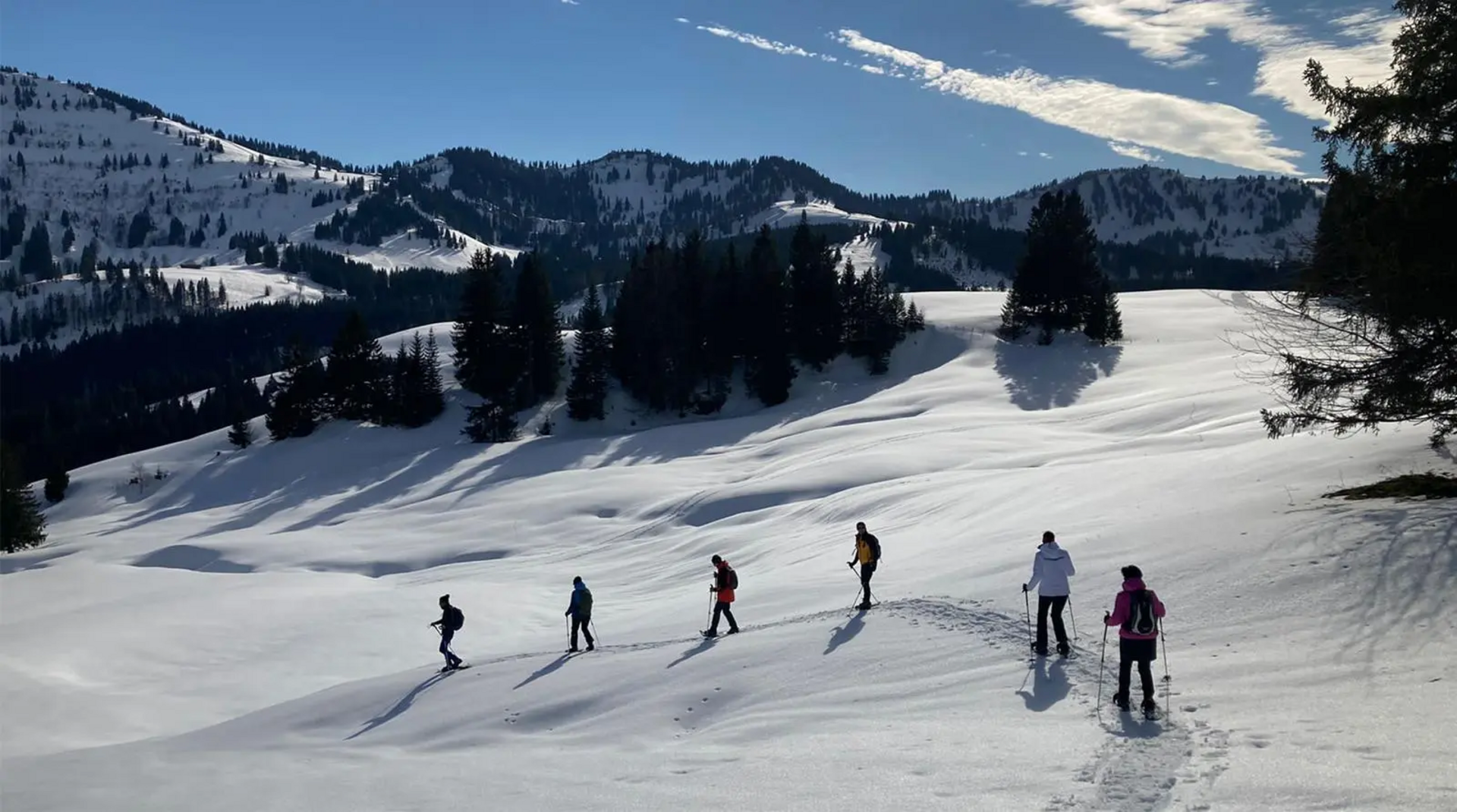 Gruppe beim Schneeschuhwandern durch verschneite Berglandschaft