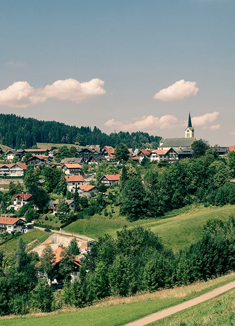 Panoramaaufnahme von Oberstaufen mit grünen Hügeln und Kirche im Hintergrund.