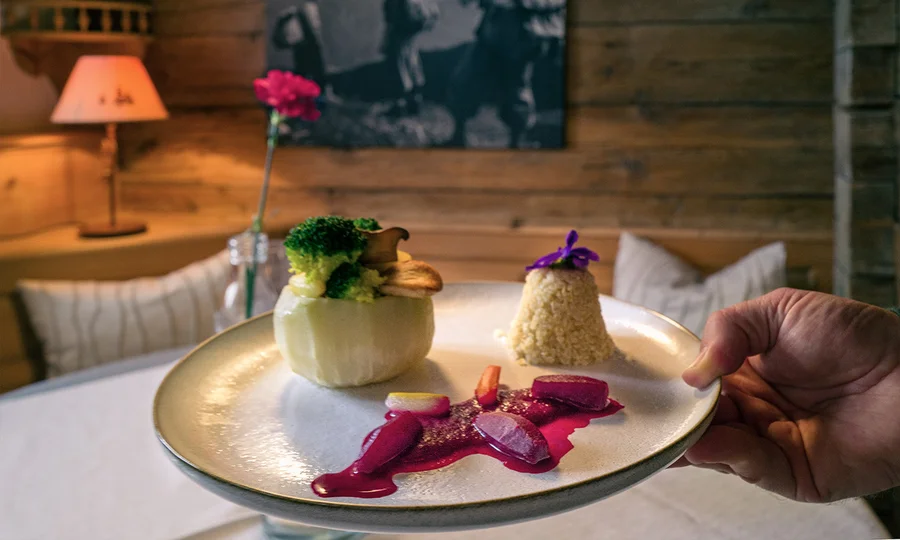Kreativ angerichtetes Dessert mit Gemüse, Sauce und essbarer Blüte auf edlem Porzellanteller – serviert im gemütlichen Restaurant des Hotel Birkenhof in Oberstaufen