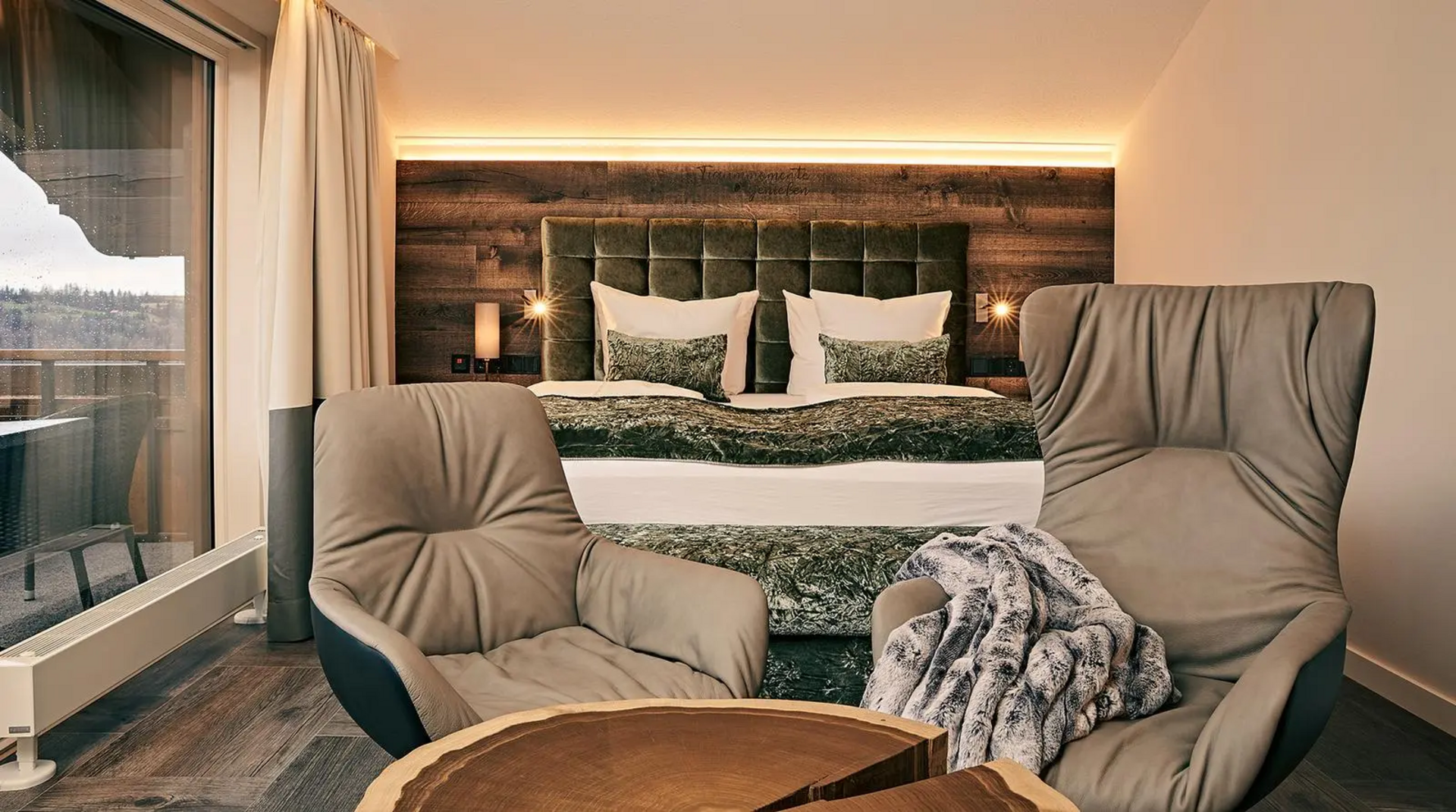 Doppelzimmer mit Balkonblick und zwei gemütlichen Sesseln vor dem Bett.