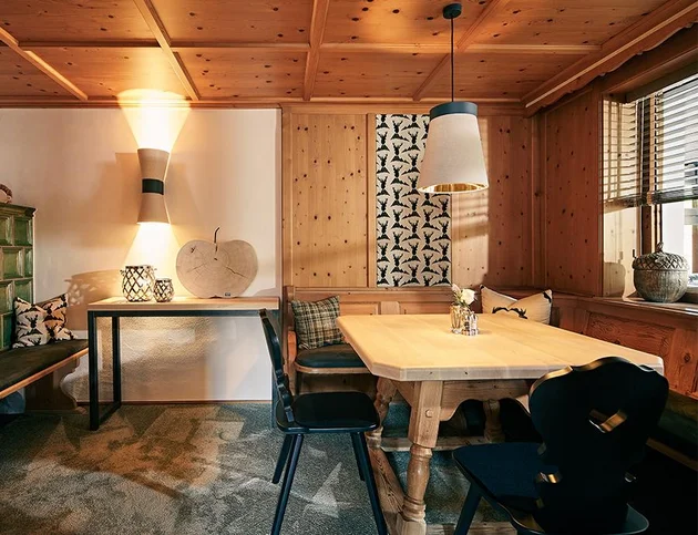 Gemütlich eingerichtetes Kaminzimmer mit Holzwänden, traditionellem Mobiliar und stimmungsvoller Beleuchtung im Hotel Birkenhof.