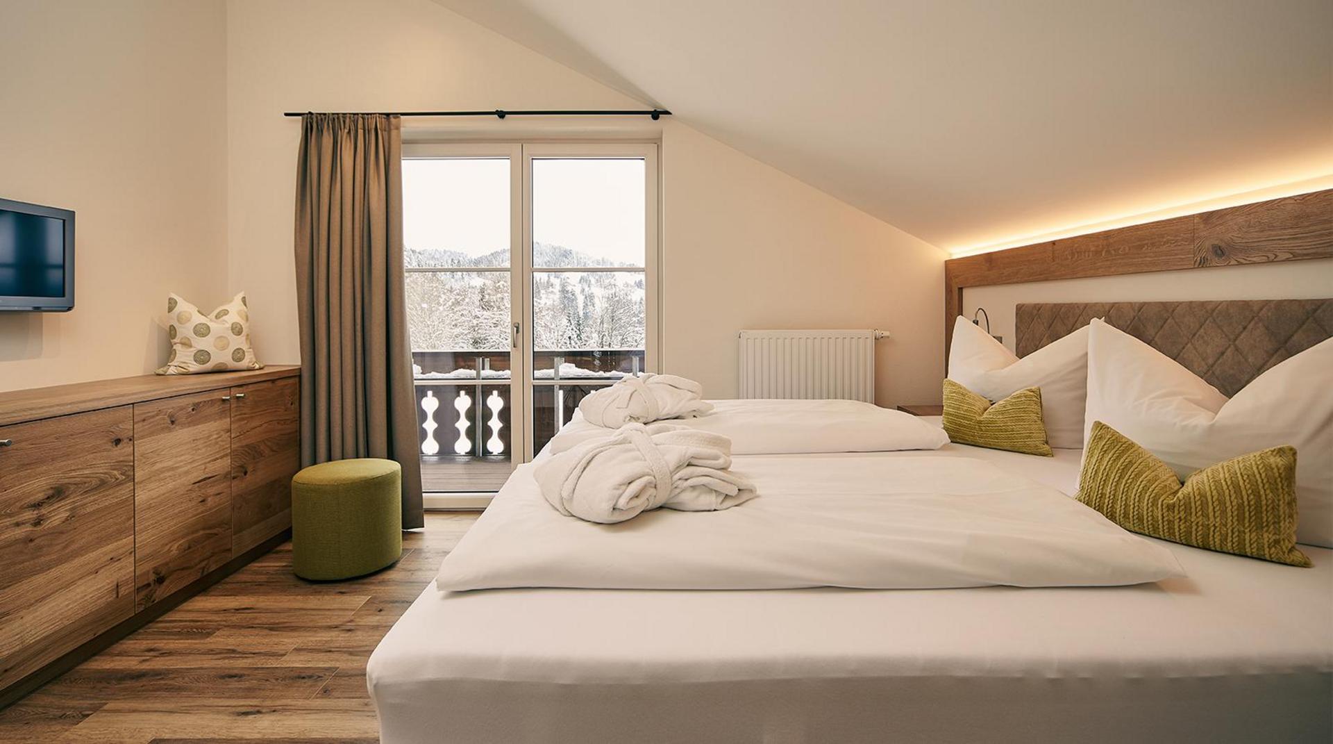 Doppelzimmer mit großem Bett, grünen Kissen und Balkonblick.