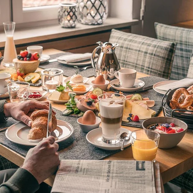 reich gedeckter Frühstückstisch mit Cappuccino Croissants Früchten Orangensaft Buffet 