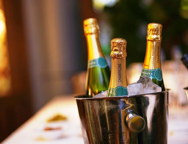 Champagnerflaschen in einem silbernen Kühler mit Eiswürfeln auf einem Tisch