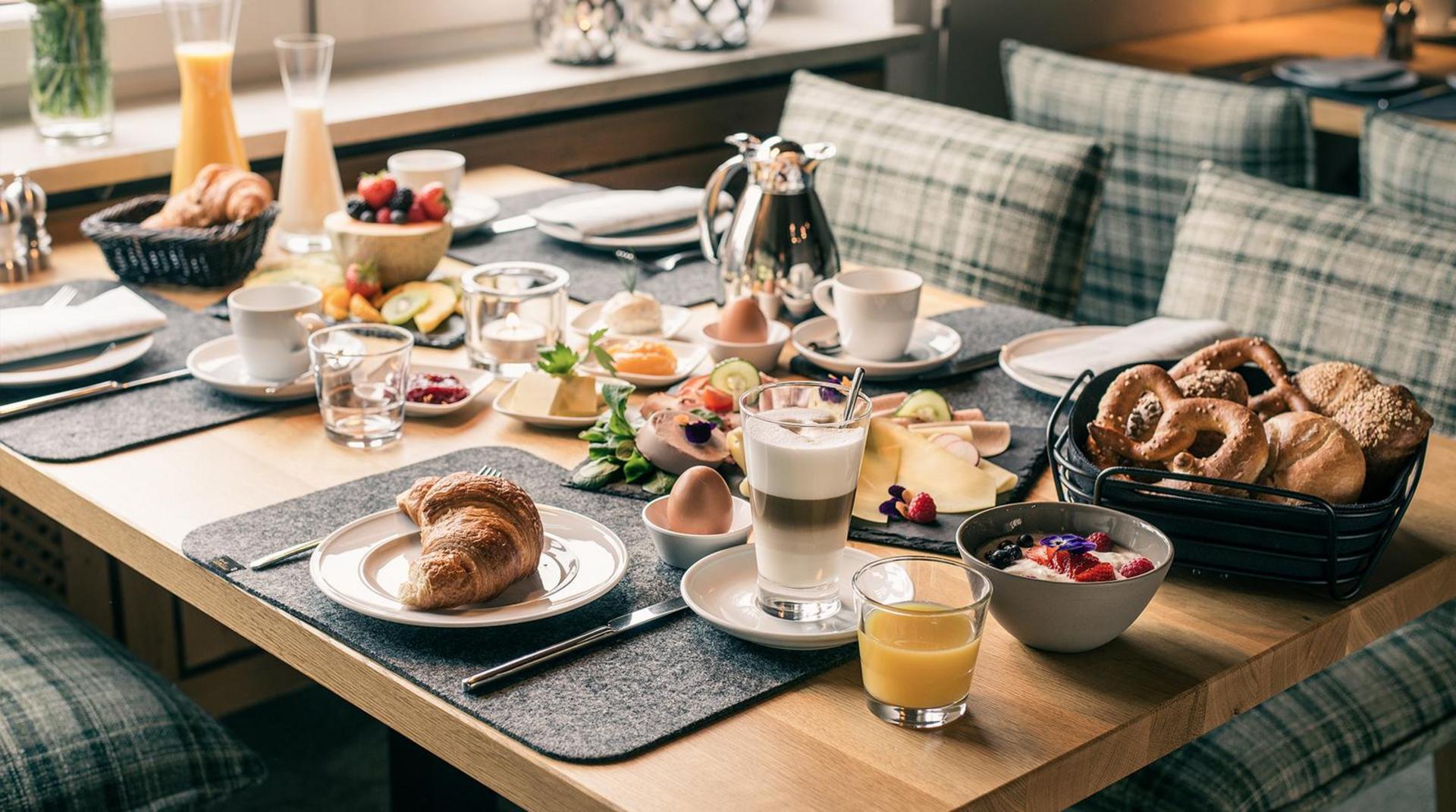 gedeckter Frühstückstisch mit Croissants Früchten Obst Orangensaft Kaffee