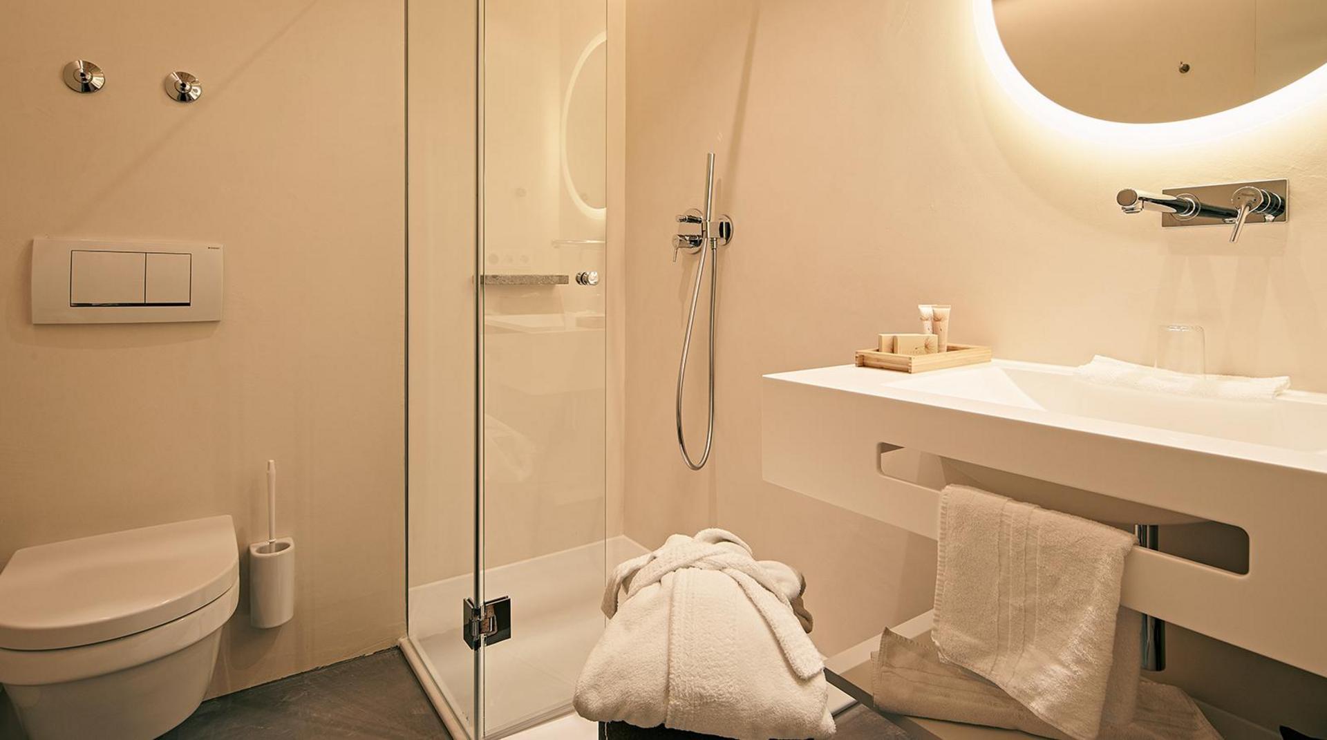 Modernes Bad mit Glasdusche, WC und hellem Waschtisch.