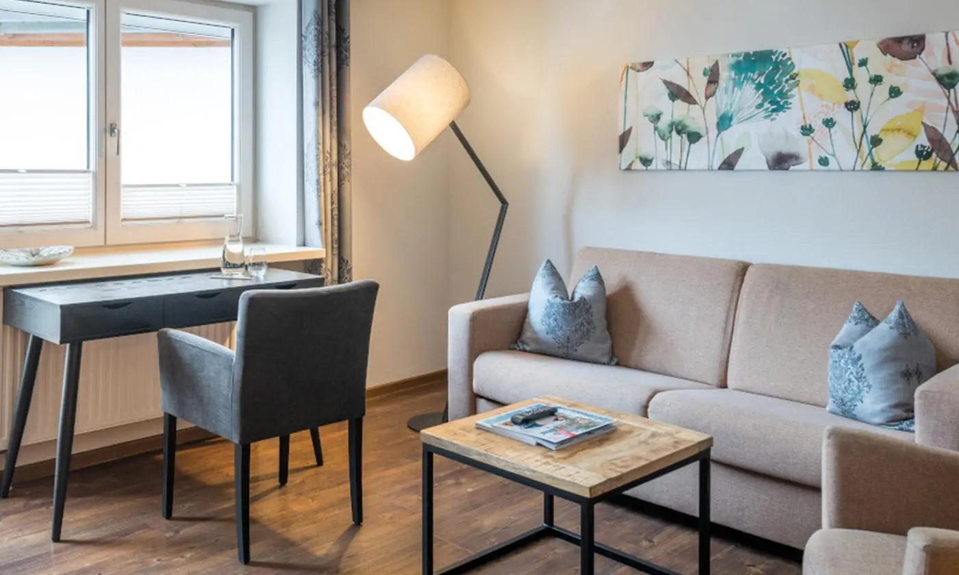 Helles Wohnbereich-Zimmer mit Schreibtisch, Sessel, Sofa und Stehlampe im modernen Stil