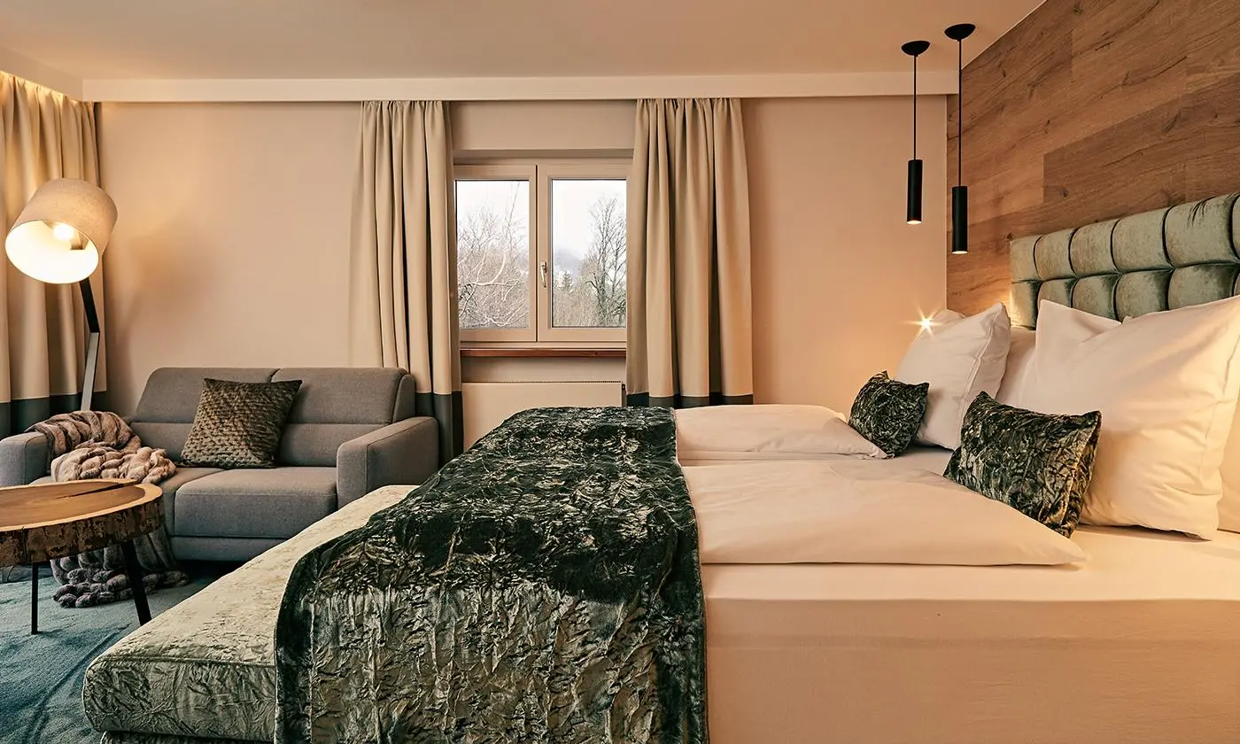Modernes Zimmer mit Doppelbett, Sofa, Holztisch und großen Fenstern mit Vorhängen