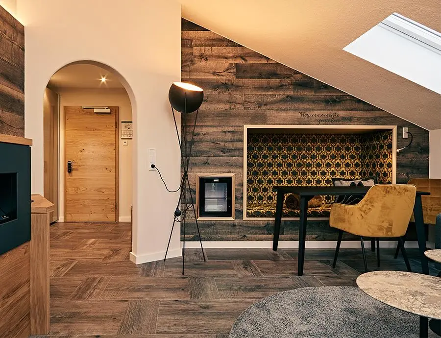 Eingangsbereich einer Suite mit Rundbogen, Holztür, Holzwand, integrierter gepolsterter Sitznische, Schreibtisch und gelbem Stuhl unter Dachschräge