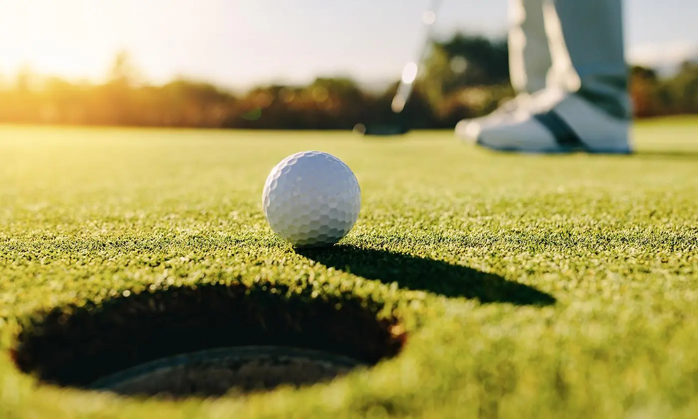 Golfball auf grünem Rasen, umgeben von gepflegter Golfplatzlandschaft