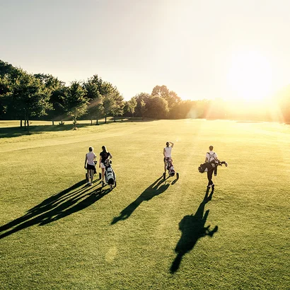 Gruppe von Golfern beim Spaziergang über den Golfplatz in der Abendsonne – Hotel Birkenhof Oberstaufen Allgäu