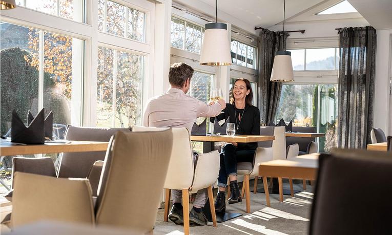 Paar stößt im Restaurant des Hotel Birkenhof in Oberstaufen mit Wein an