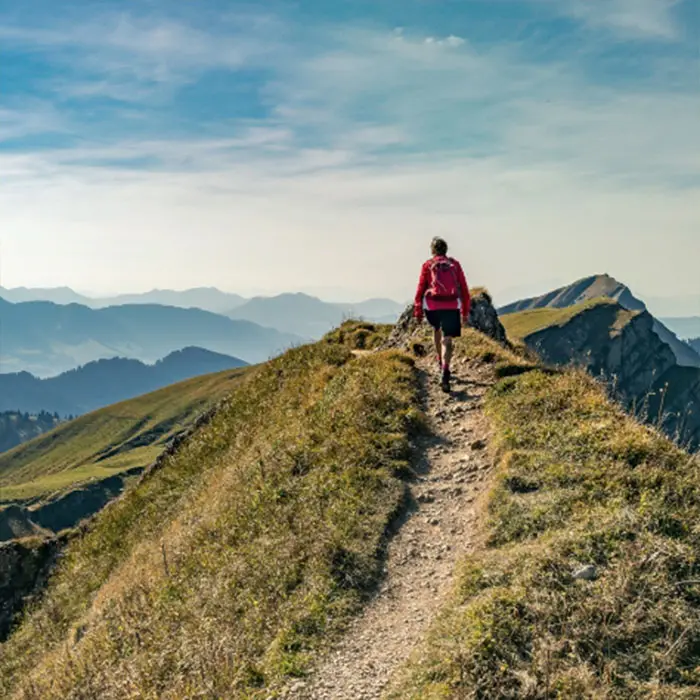 Hikers on a narrow mountain path with an impressive Alpine panorama in the Allgäu.