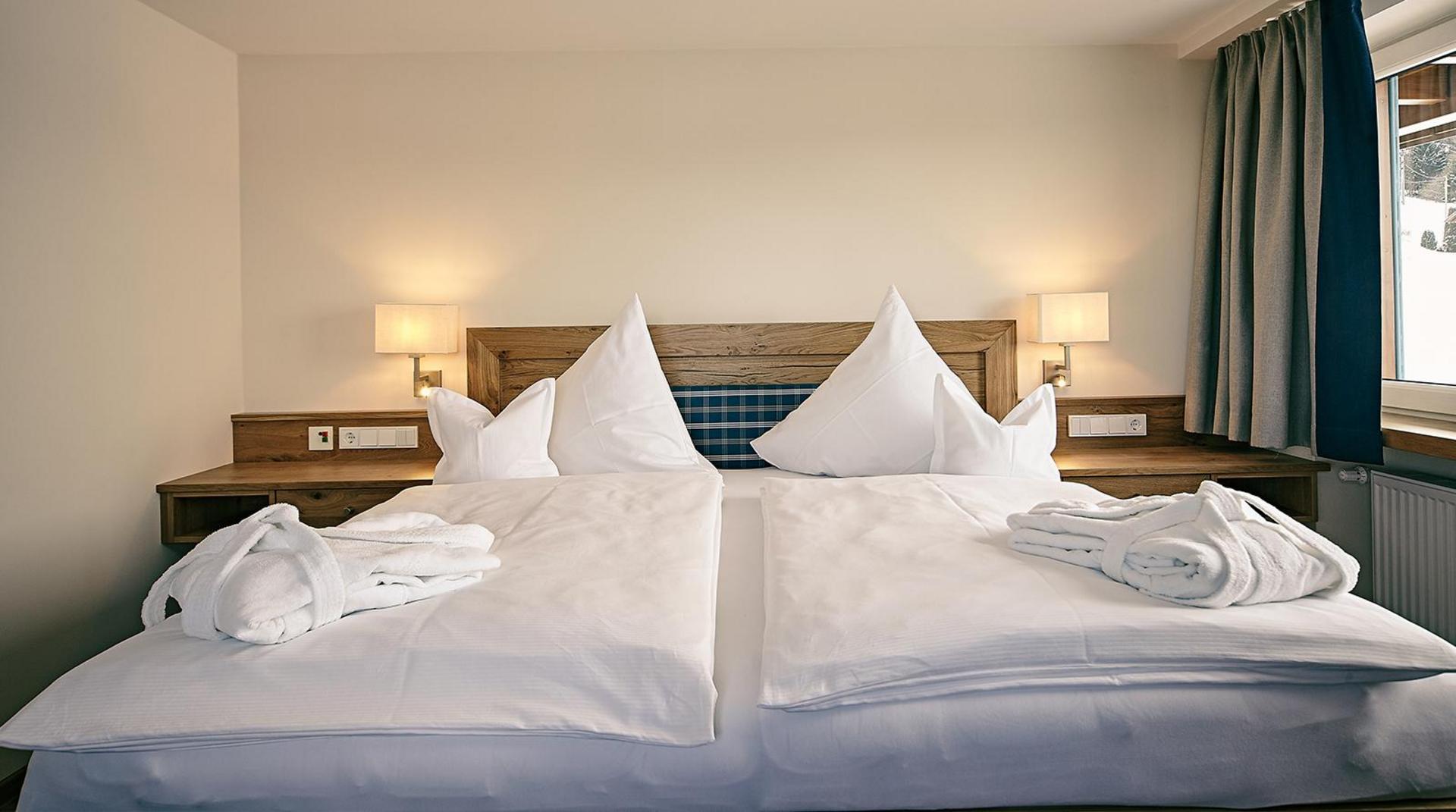 Doppelzimmer mit großem Bett, weißen Kissen und Bademänteln.