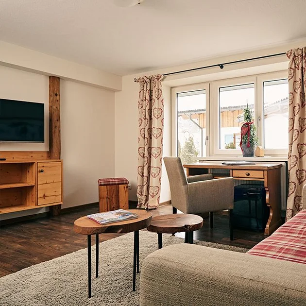 Living area with desk and TV in a suite at the Hotel Birkenhof Oberstaufen in the Allgäu