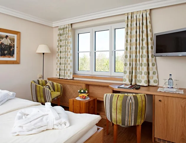 Doppelzimmer mit Schreibtisch, zwei Stühlen und Blick aus dem Fenster.