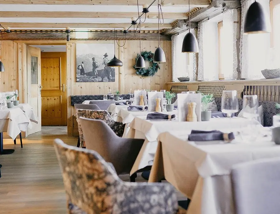 Gemütlich eingerichtetes Restaurant im Hotel Birkenhof mit Holzwänden, weißen Tischdecken und stilvollen Lampen
