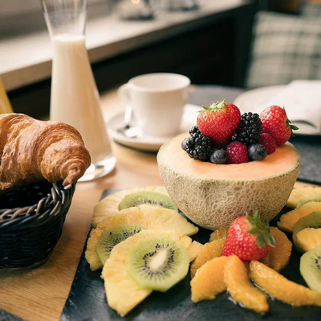 Früchteteller und Croissant Milch Kaffeetasse auf Frühstückstisch