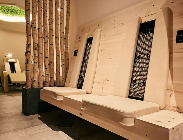 Infrarot-Wärmeliegen im Wellnessbereich des Hotels Birkenhof, mit Holzverkleidung und separaten Entspannungsstühlen im Hintergrund.