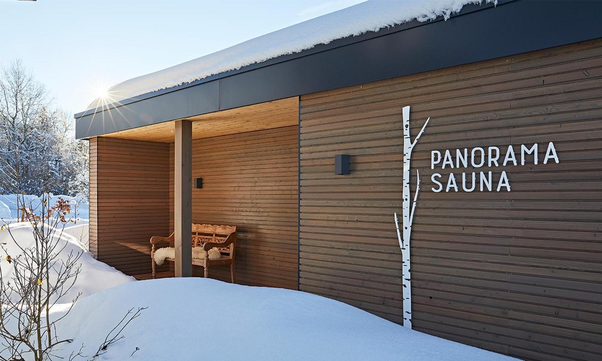 Panoramasauna Winter Hotel Birkenhof Oberstaufen Allgäu Außenansicht einer modernen Holzsauna im Schnee mit der Aufschrift „Panorama Sauna“