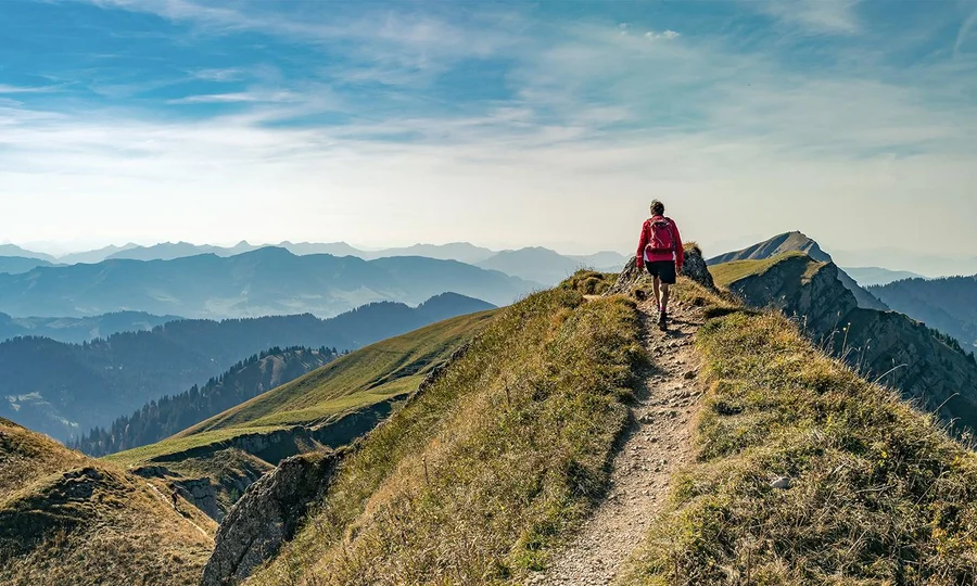 Wanderer auf schmalem Bergpfad mit beeindruckendem Panorama am Hochgrat bei Oberstaufen