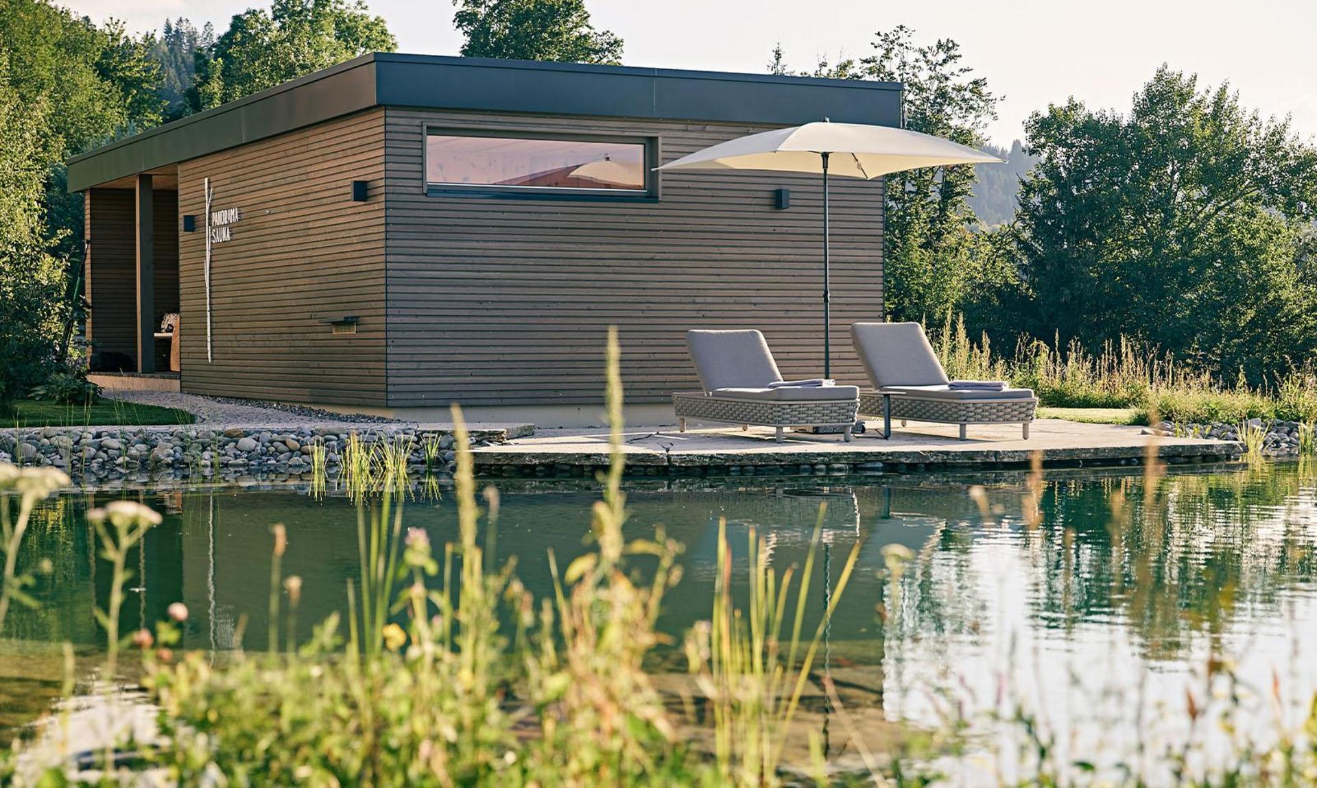 Außenaufnahme eines Hotels in den Bergen mit Naturbadeteich und Panorama-Sauna