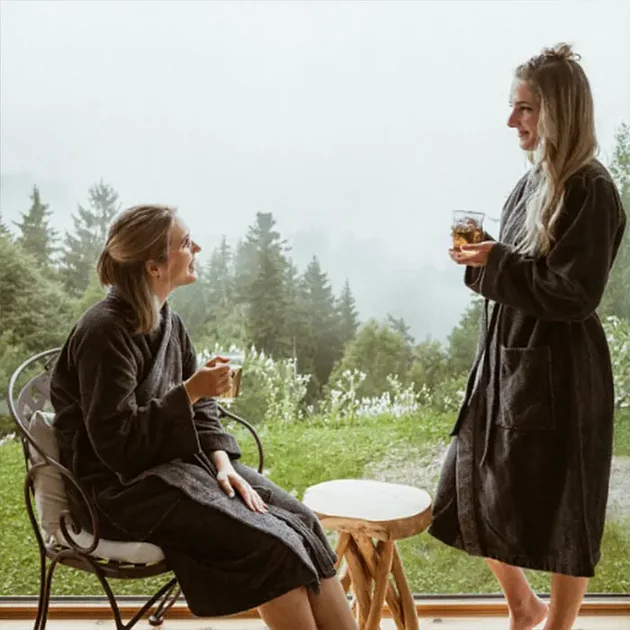 Zwei Frauen im Bademantel trinken Tee mit Blick ins Grüne im Hotel Birkenhof Oberstaufen.