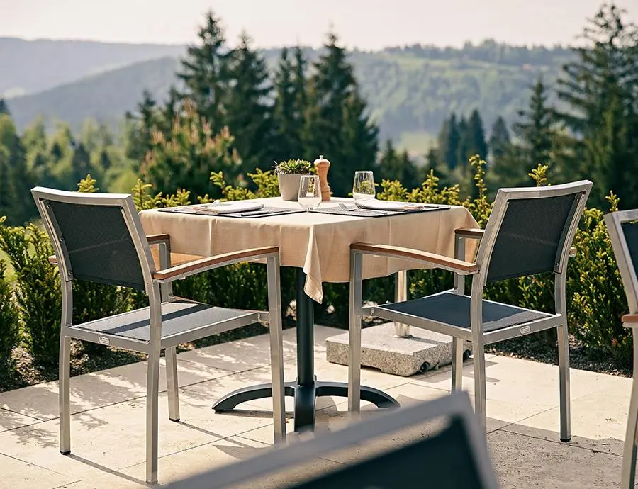 Frühstückstisch mit vier Stühlen auf der Terrasse des Hotel Birkenhof, umgeben von Natur und Blick auf das Allgäuer Hügelland.