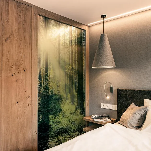 Modern eingerichtetes Einzelzimmer mit gemütlichem Bett, hölzerner Wandverkleidung und dekorativem Wandbild eines Waldes, das eine beruhigende Atmosphäre schafft.
