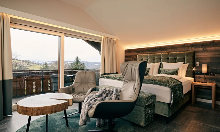 Luxuriöses Zimmer mit großem Bett, Sitzbereich, Couchtischen und Panoramablick durchs Fenster
