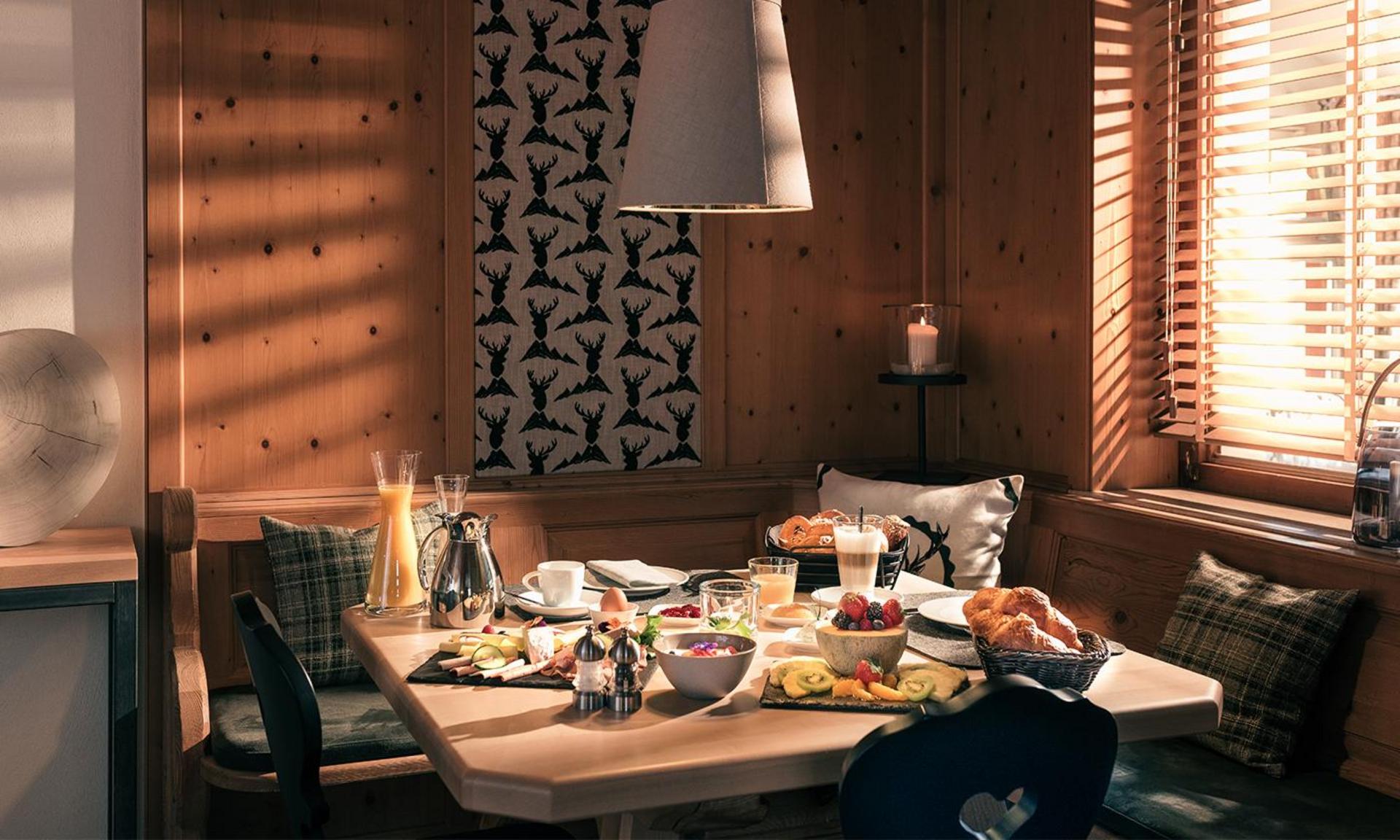 Reich gedeckter Frühstückstisch in gemütlicher Holzstube mit frischen Brötchen, Obst und Getränken – Hotel Birkenhof in Oberstaufen