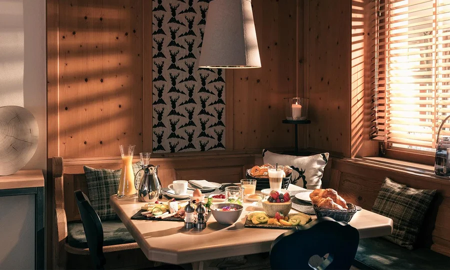 Reich gedeckter Frühstückstisch in gemütlicher Holzstube mit frischen Brötchen, Obst und Getränken – Hotel Birkenhof in Oberstaufen