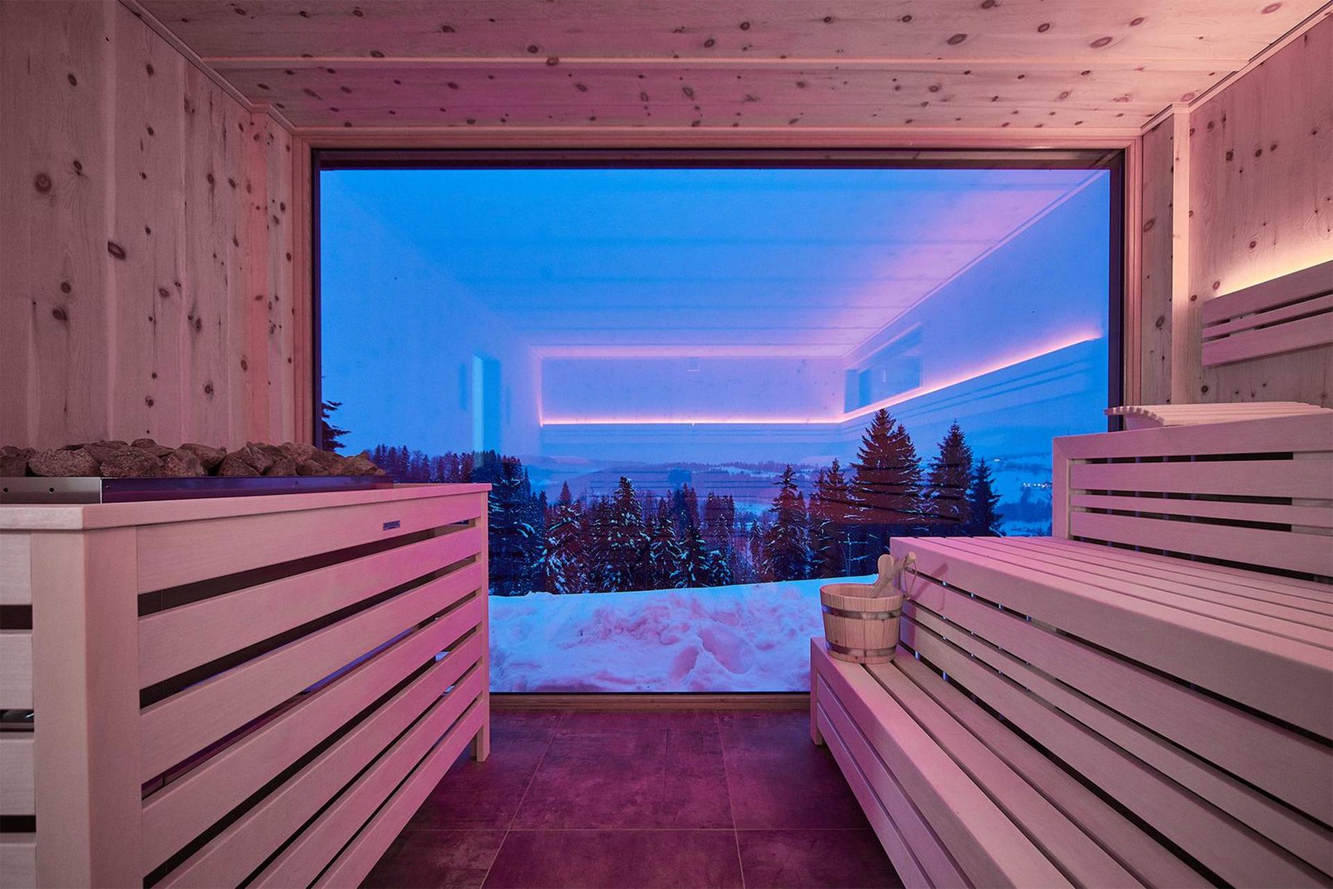 Winteransicht des modernen Spa-Gebäudes mit schneebedecktem Dach und umliegender Winterlandschaft.