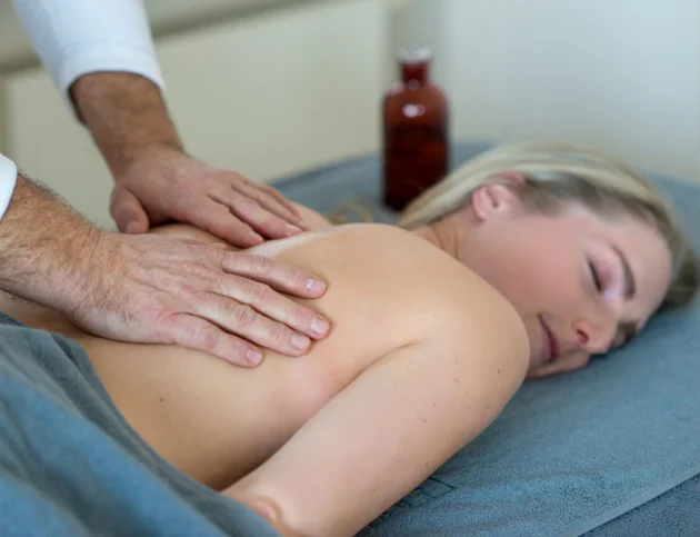 Eine Person liegt entspannt auf der Massageliege, während eine Rückenmassage durchgeführt wird.
