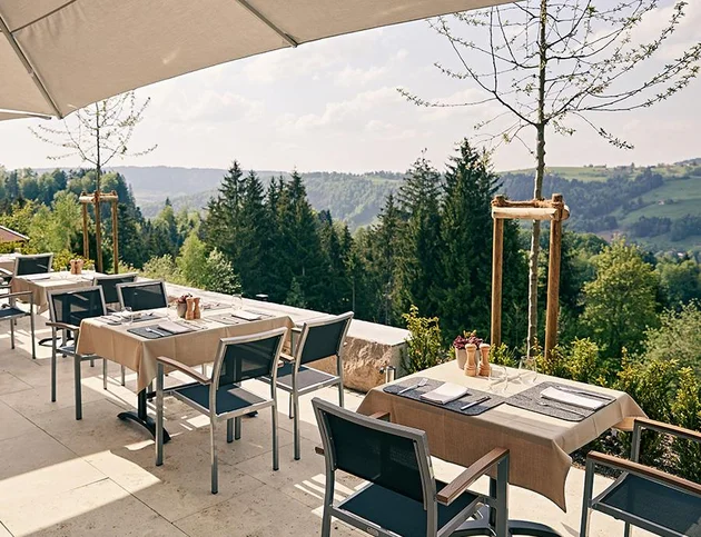 Terrasse des Hotel Birkenhof mit gedeckten Tischen und Panoramablick auf die grüne Hügellandschaft im Allgäu