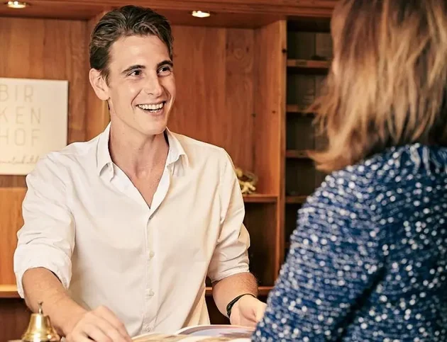 Rezeptionist begrüßt Gast an der Rezeption.