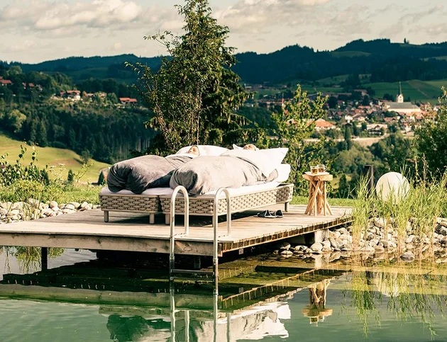 Außenbett am Naturteich mit Blick auf die umliegende Hügellandschaft.
