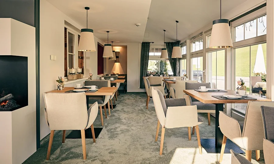Heller Restaurantbereich mit modernen Lampen und gemütlicher Einrichtung im Hotel Birkenhof mit Blick auf die Terrasse