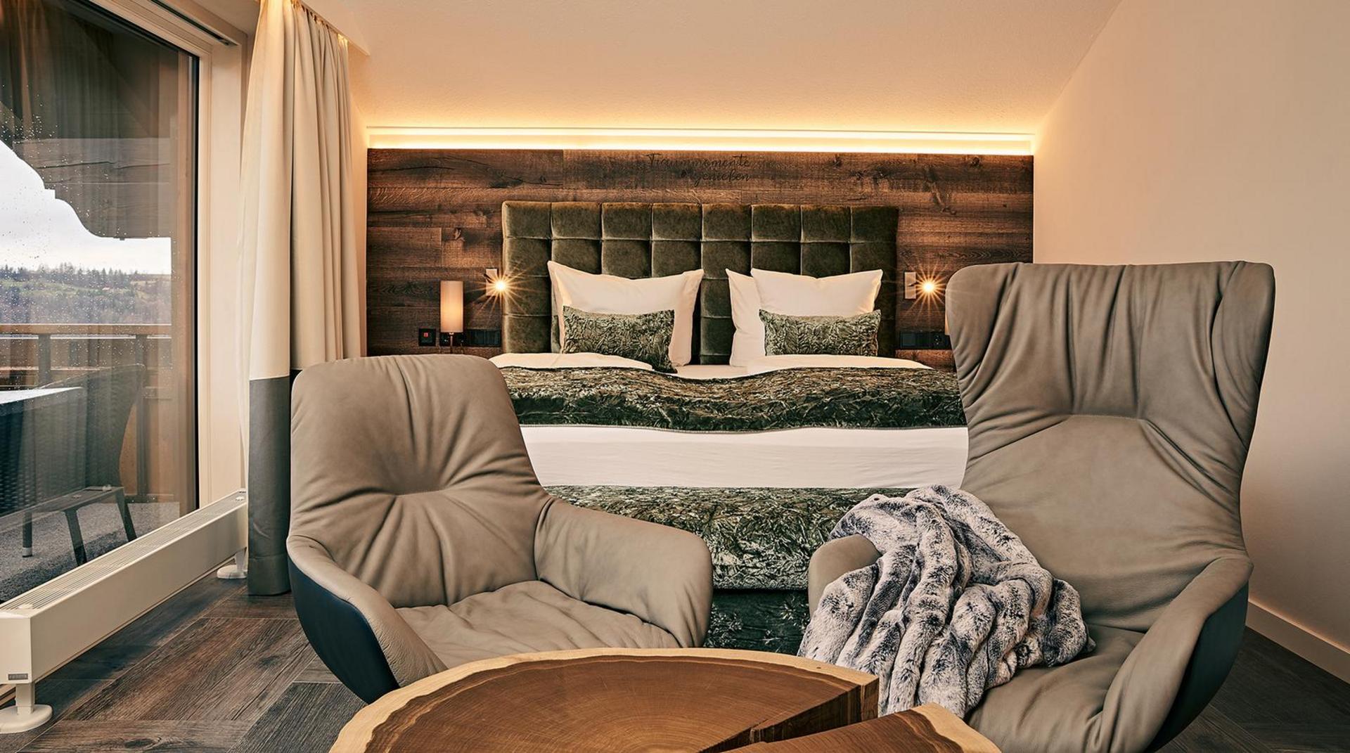 Doppelzimmer mit Balkonblick und zwei gemütlichen Sesseln vor dem Bett.