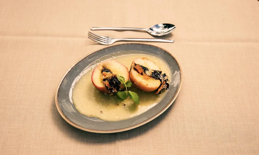 Gebackene Äpfel mit Füllung auf Vanillesauce, garniert mit Minze.