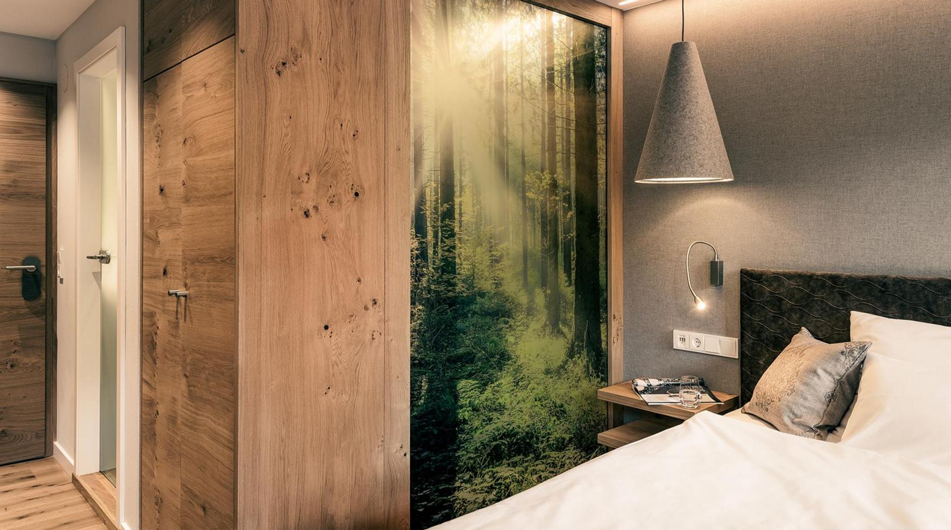 Doppelzimmer mit Waldfotomotiv an der Wand und Holzdetails.