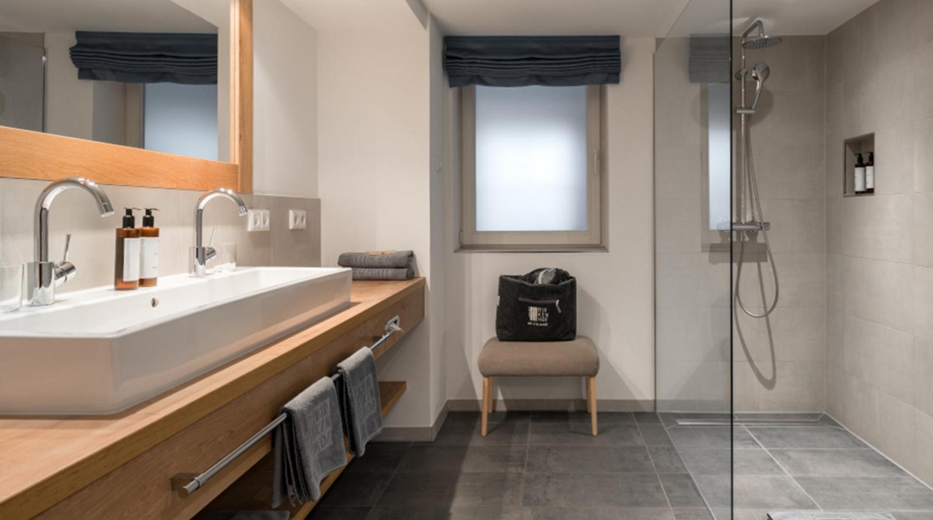 Modernes Bad mit bodengleicher Dusche, Doppelwaschtisch und großem Spiegel.