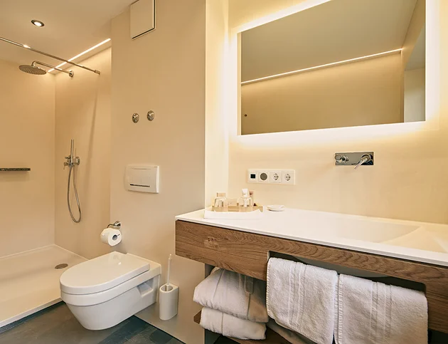 Modernes Badezimmer mit begehbarer Dusche, WC und beleuchtetem Spiegel