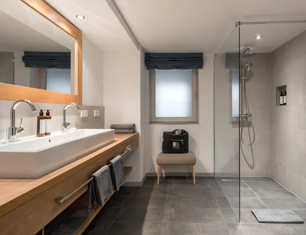 Modernes Bad mit Doppelwaschbecken, Glasdusche und schlichter Eleganz im Hotel Birkenhof Oberstaufen.