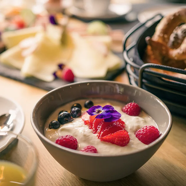 Müsli mit Früchten und Brezel und Käseteller auf dem Frühstückstisch