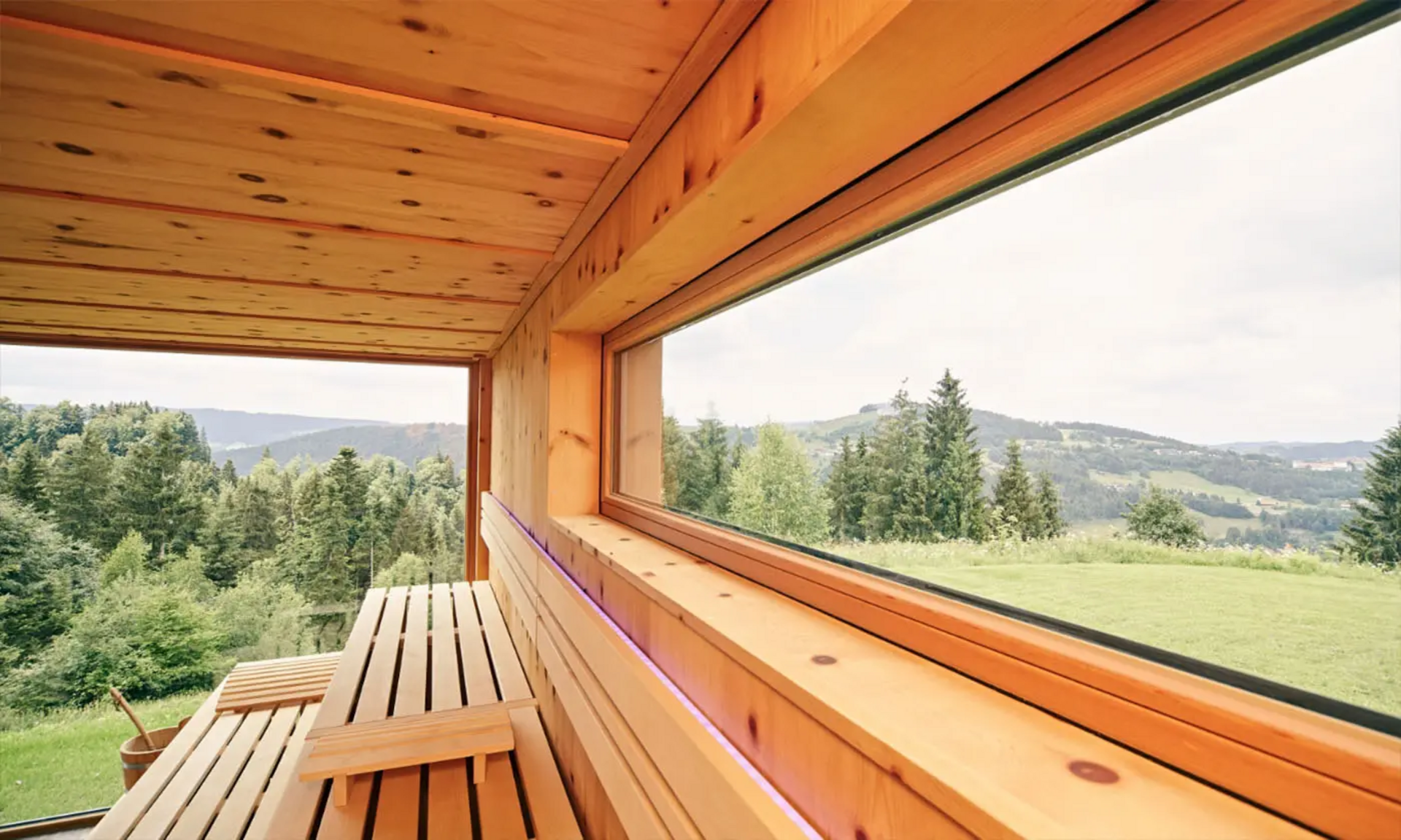 Holzsauna im Birkenhof Oberstaufen mit Panoramafenster und Blick auf die Allgäuer Landschaft.