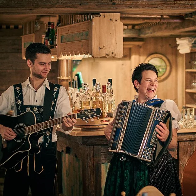 Zwei Musiker mit Gitarre und Akkordeon spielen in der Gaststube für die Gäste