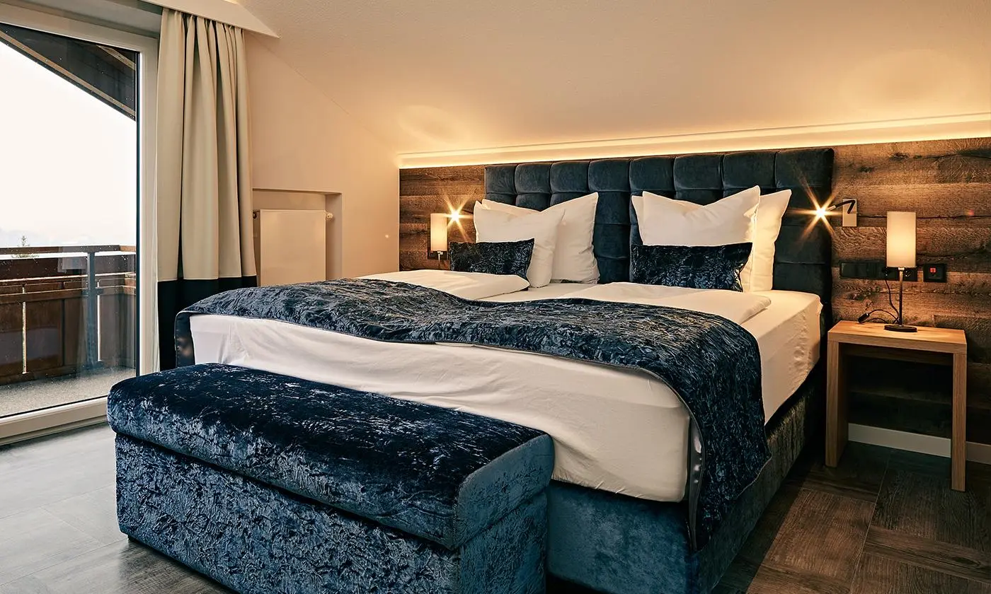 Elegantes Doppelzimmer mit blauem Bezug, Sitzbank und Zugang zum Balkon