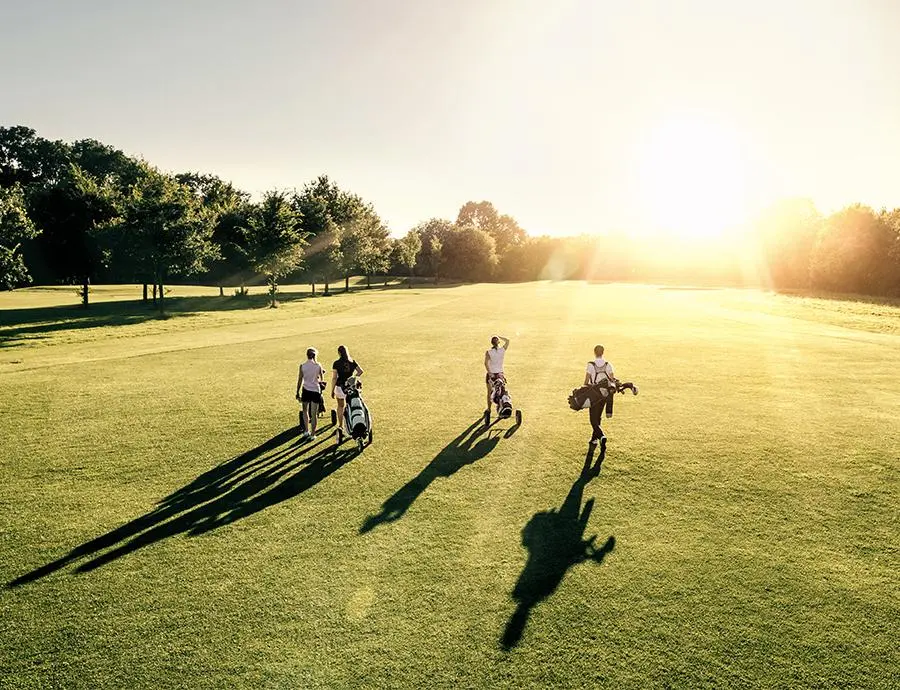 Gruppe von Golfern beim Spaziergang über den Golfplatz in der Abendsonne – Hotel Birkenhof Oberstaufen Allgäu