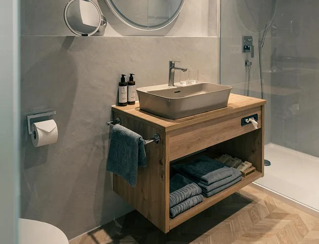 Badezimmer mit begehbarer Dusche, Holzwaschtisch und Spiegel.